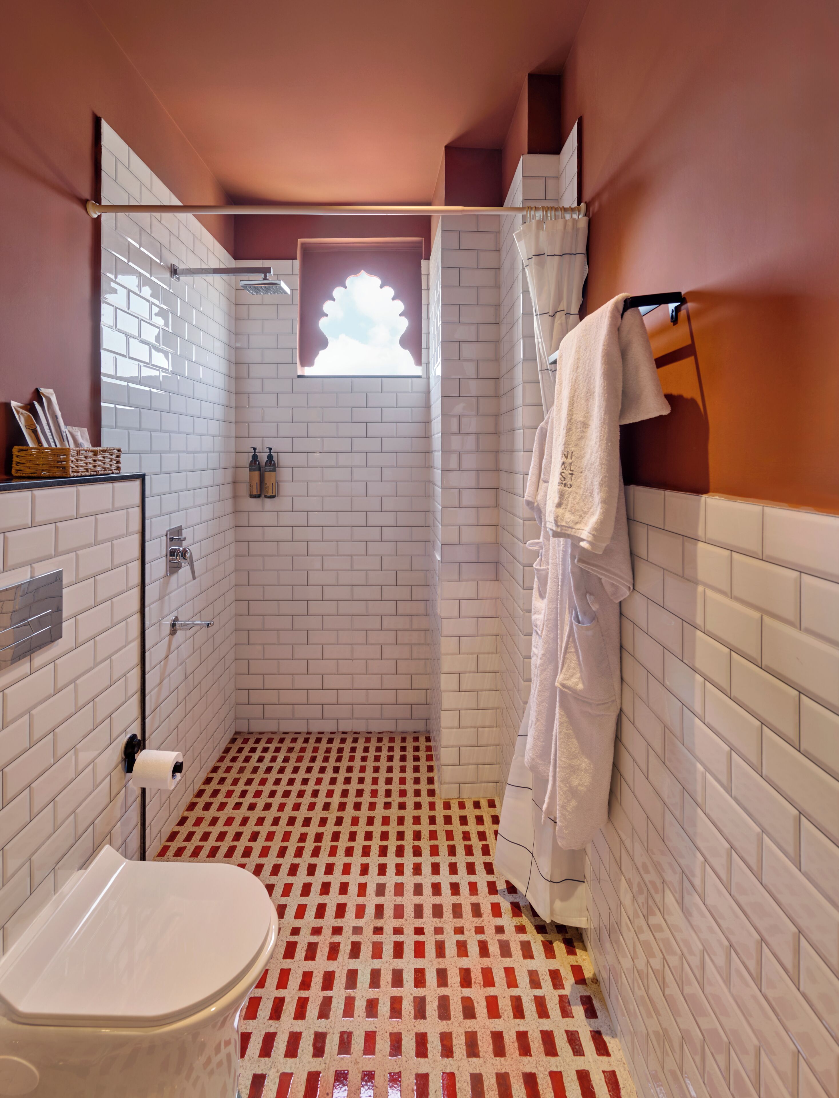 Un baño con ducha, inodoro y suelo a cuadros rojo y blanco.