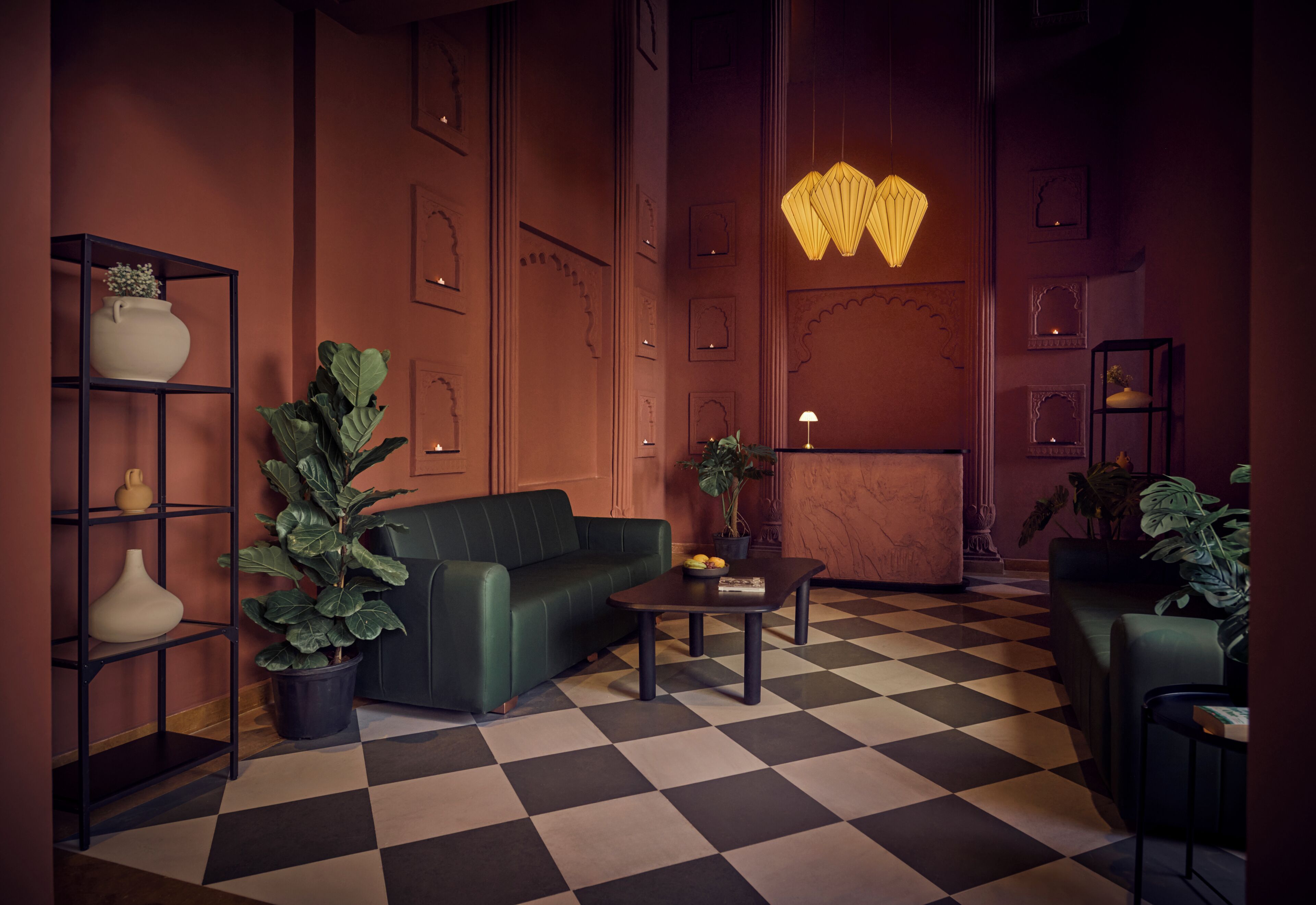 A room with a checkered floor, a green sofa, a coffee table, and a bookshelf with plants.