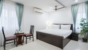 A hotel room with a bed, a desk with chairs, a ceiling fan, an air conditioning unit, and a potted plant. - RCC Hotels Park View Inn Miyapur (Hyderabad)