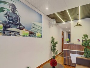 A reception area with a Buddha statue mural, a reception desk, and a fan on the ceiling. - RCC Hotels Park View Inn Miyapur (Hyderabad)