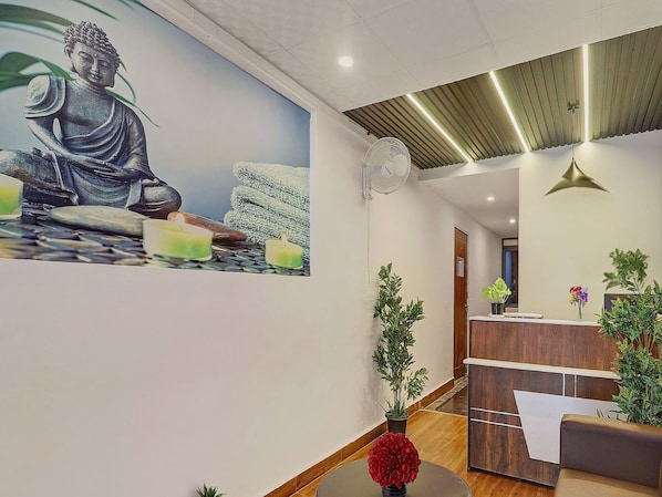 A reception area with a Buddha statue mural, a reception desk, and a fan on the ceiling.