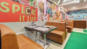 Un restaurante con un mural vibrante en la pared, asientos tipo cabina y un suelo cubierto de alfombra verde.