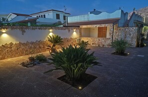 Une cour bordée de murs en pierre, agrémentée de plantes en pot et dotée d’un espace extérieur bien éclairé.