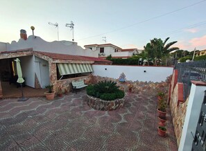 Une terrasse avec un mur en pierre, un banc et des plantes en pot.