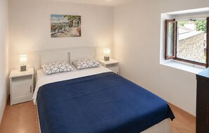 A bedroom with a bed, two bedside tables with lamps, a window with a view, and a painting on the wall. - Amazing home in Podgradina with private swimming pool, can be inside or outside (Podgradina)