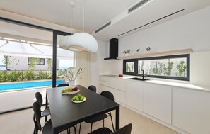 Eine moderne Küche mit Essbereich, großen Fenstern und Blick auf einen Pool.
