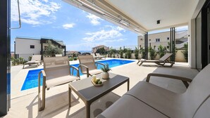 En balkon med pool, liggestole og et bord med stearinlys og bakke.