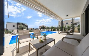 A balcony with a pool, lounge chairs, and a table with candles and a tray. - Luxurious home in Pakostane (Pakostane)
