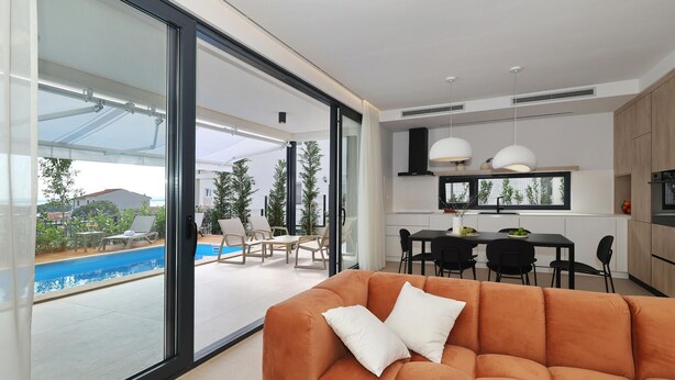 En moderne opholdsstue med pool, spiseområde og køkken.