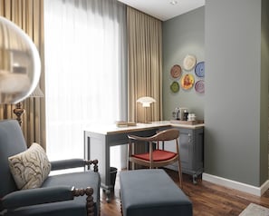 Une chambre moderne équipée d’un bureau, d’une chaise et d’un pouf, d’une lampe, ainsi que d’un mur décoré d’assiettes.
