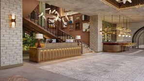 Eine Lobby mit Empfangstresen, Treppe und Barbereich.