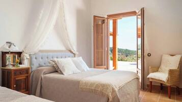 A bedroom with a bed, a nightstand, a chair, and an open door leading to a balcony.