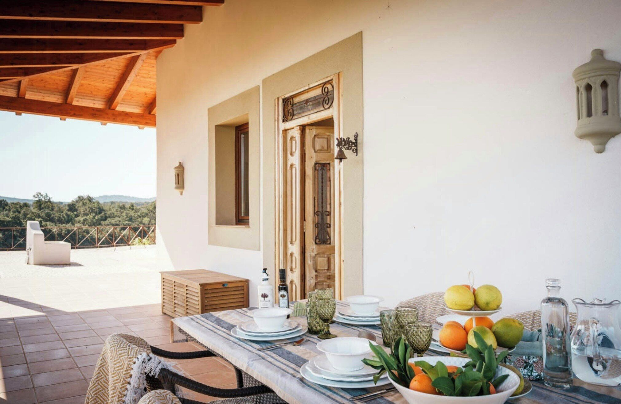 A terrace with a table set for dining, a door, and a view of the landscape.