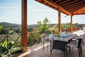 Un espace extérieur abrité, aménagé pour les repas, avec une table pour deux, entourée de chaises, et offrant une vue sur un paysage pittoresque.
