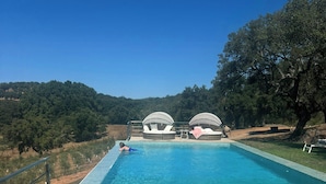 A rectangular swimming pool with clear blue water, surrounded by a tiled deck. In the background, there are two large, dome-shaped structures, possibly for shade or shelter.