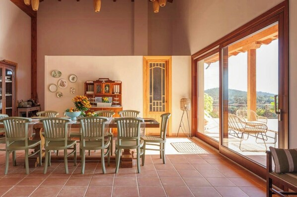 Un coin repas comprenant une table et des chaises, un meuble décoratif et une vue à travers une porte vitrée.
