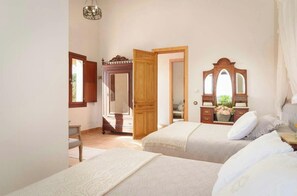 Une chambre avec deux lits, une armoire en bois, un miroir et une fenêtre.