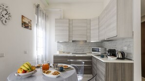 A modern kitchen with a dining table set for breakfast, a microwave, and a coffee maker. - VIA TAGIURA 25/27 - For Work and Leisure (Milan)
