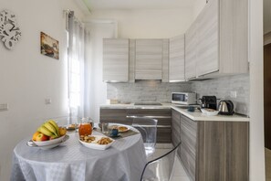 A modern kitchen with a dining table set for breakfast, a microwave, and a coffee maker. - VIA TAGIURA 25/27 - For Work and Leisure (Milan)