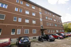 A multi-story building with a parking area in front. - VIA TAGIURA 25/27 - For Work and Leisure (Milan)