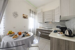 A modern kitchen with a dining area, featuring a round table with breakfast items, a coffee machine, and a kettle. - VIA TAGIURA 25/27 - For Work and Leisure (Milan)