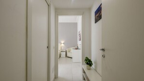 A hallway leading to a bedroom with a bed, bedside table, and a nightstand. - VIA TAGIURA 25/27 - For Work and Leisure (Milan)