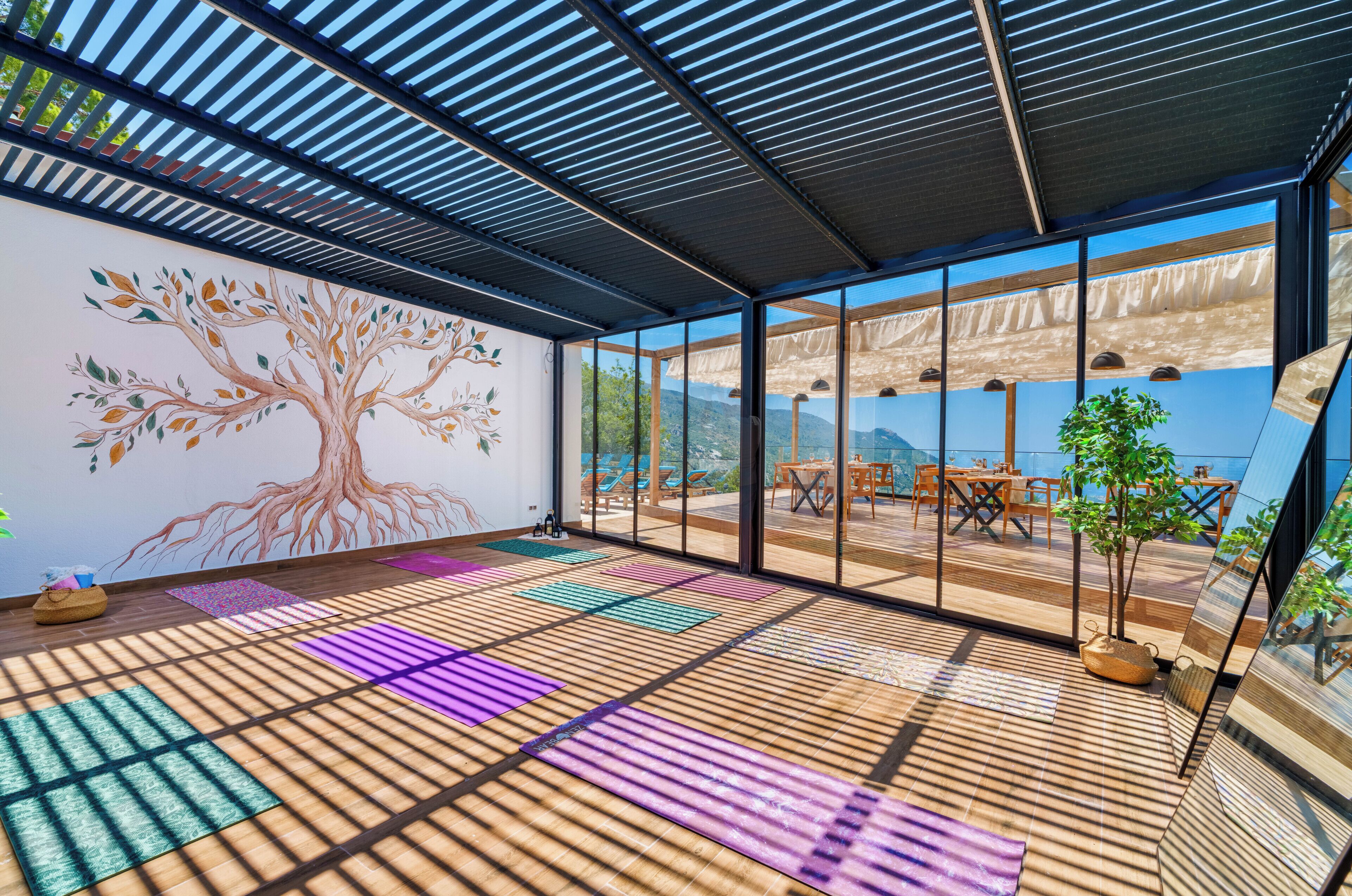 A room with tatami mats, a tree mural, large windows, and outdoor seating.