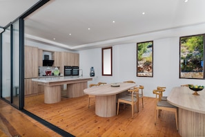A modern kitchen with wooden cabinets, a central island, and a dining area with wooden chairs. - Turquoise Retreat Wellness & Spa (Kaş)
