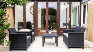 A patio area with wicker furniture, a small table, and a glass door leading to an interior space.