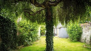 A garden with a tree, a brick wall, and a shed. - Cozy House Between the City and the Beach with a Private Garden (Dunkerque)