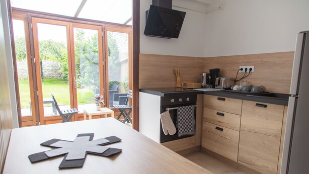 A kitchen with wooden cabinets, a built-in oven, a sink, and a dining area with a table and chairs.