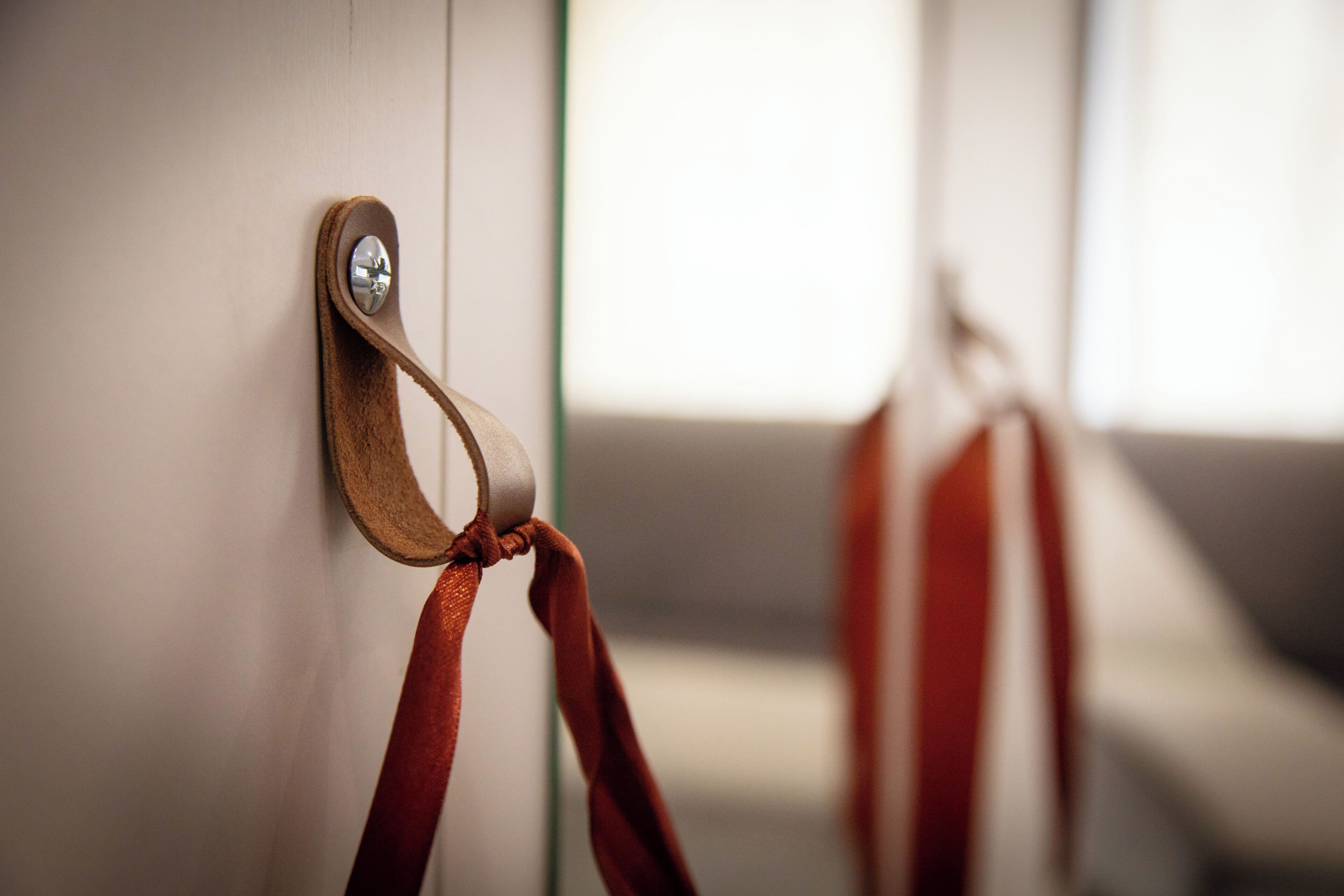 A close-up of a wall-mounted hook with a brown strap.