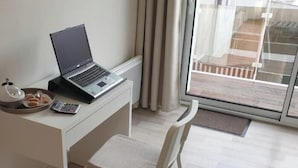 A laptop on a desk with a cup and a plate of pastries, a chair, and a view of a building through a glass door. - Les clés de la mer (Le Portel)