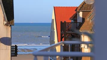 A coastal building with a red roof, a balcony, and a view of the sea.