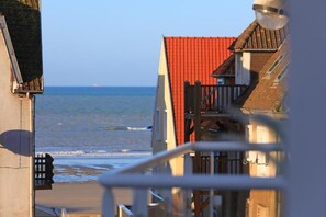 Un bâtiment situé sur la côte, avec un toit rouge, un balcon et une vue sur la mer.