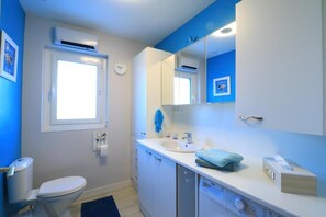 A bathroom with a toilet, sink, mirror, and a window. - Les clés de la mer (Le Portel)