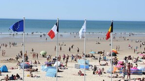 A beach with flags, tents, and people. - Les clés de la mer (Le Portel)