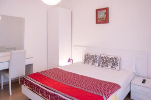 Ein Schlafzimmer mit einem Bett, einem Schreibtisch, einem Stuhl, einem Kleiderschrank und einem Nachttisch.