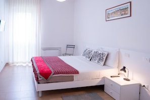 Un dormitorio con cama, mesita de noche, lámpara y un cuadro en la pared.