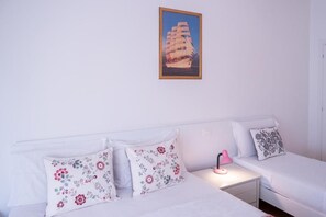 A bedroom with two beds, floral pillows, a nightstand with a lamp, and a framed picture on the wall. - ca popolo venice (Mestre)