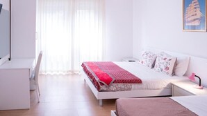 A bedroom with a bed, bedside table, desk, chair, and a window with curtains. - ca popolo venice (Mestre)