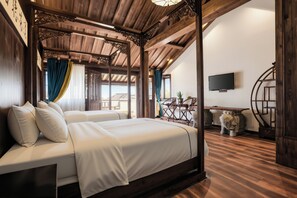 Una habitación con una cama, techo de madera y televisor montado en la pared.