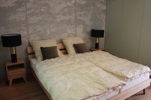 A bedroom with a bed, two bedside tables, and two lamps. - Modern wooden cottage with panoramic views, a large terrace, and air conditioning (Roznov pod Radhostem)