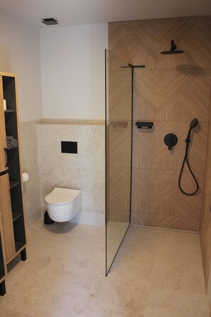 A bathroom with a toilet, a shower enclosure, and a wooden wall. - Modern wooden cottage with panoramic views, a large terrace, and air conditioning (Roznov pod Radhostem)