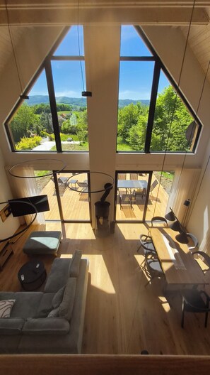A modern interior with a large skylight, wooden flooring, a sofa, and a dining area with outdoor views.