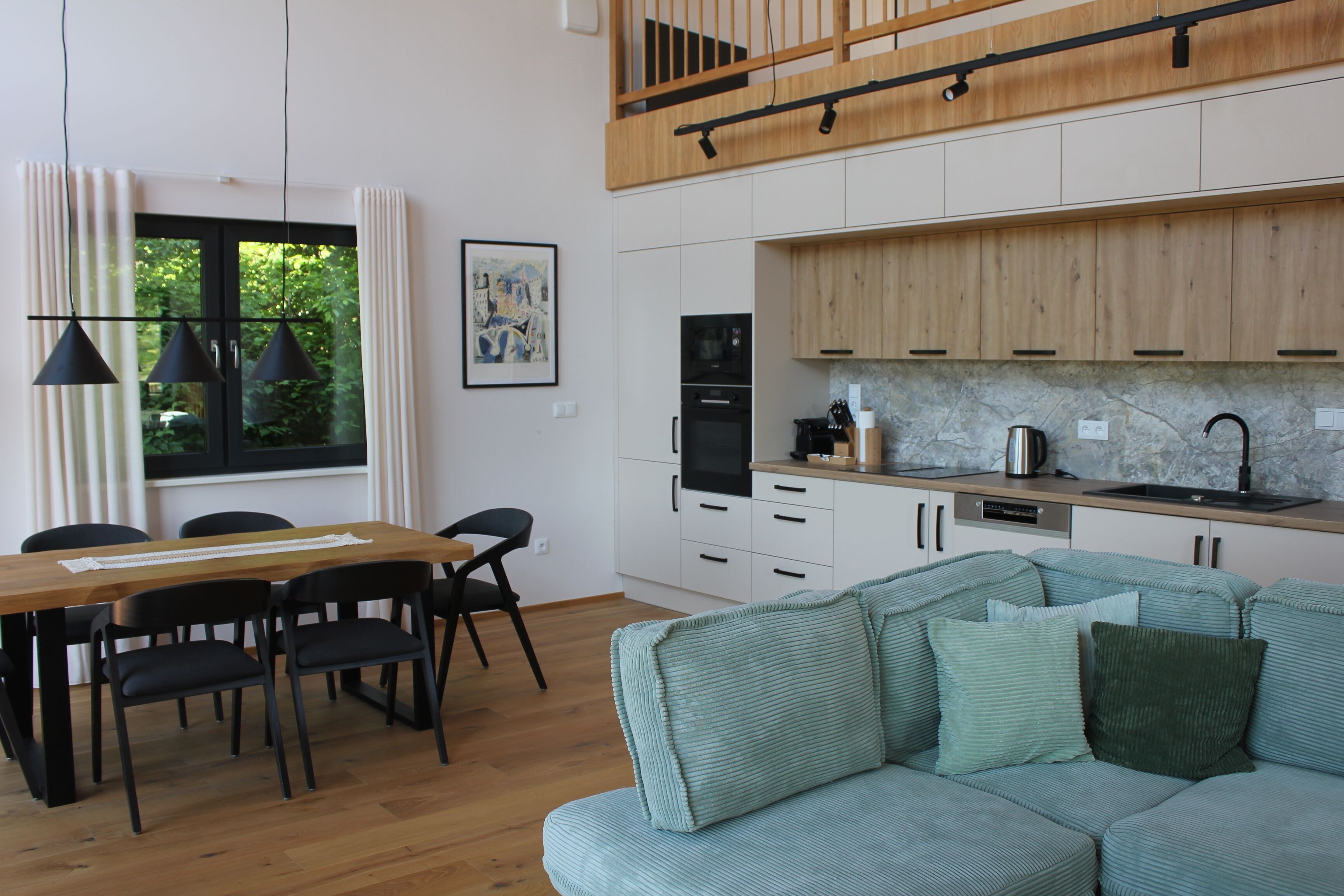 A modern kitchen with white cabinets, a wooden countertop, and a black refrigerator.