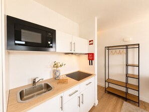 A modern kitchen with a microwave, sink, and wooden countertop. - MyStay Ribeira Hotel (Porto)
