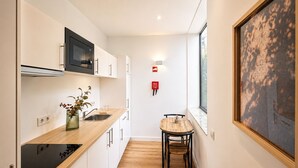 Una cocina moderna con microondas, lavamanos y encimera de madera. Hay una pequeña mesa con sillas y un cuadro en la pared.