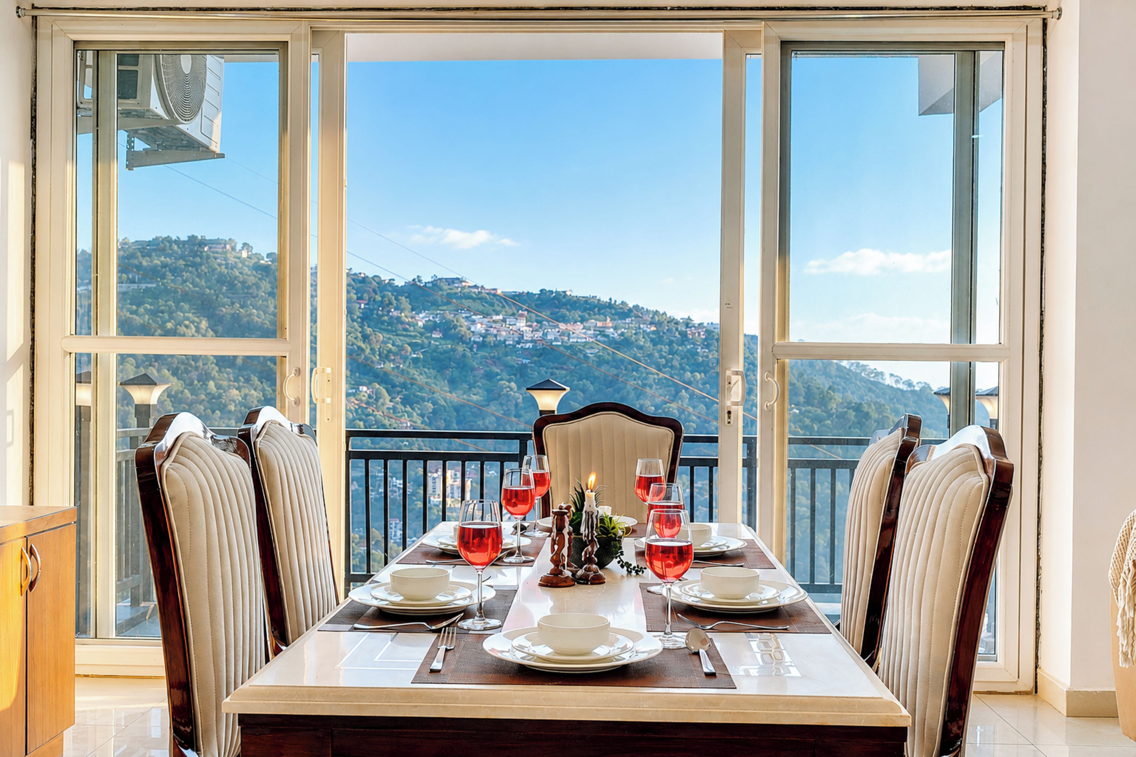 A dining table set for six with a view of a hillside.