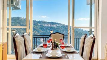 A dining table set for six with a view of a hillside.